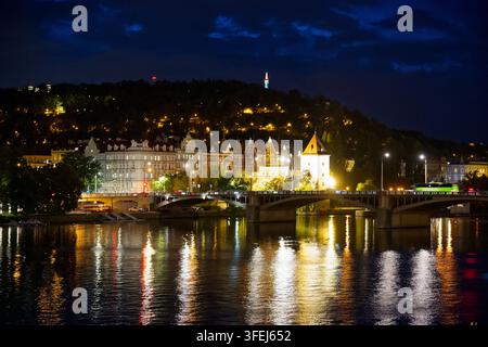 Vista notturna del ponte Jirásek sul fiume Vltava, con l'illuminato torrione dell'acqua di Malá Strana e la collina di Petřín sullo sfondo. Foto Stock