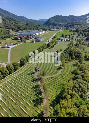 Veduta aerea del cimitero commemorativo di Srebrenica-Potocari circondato dal complesso industriale ex fabbrica di batterie e dalle colline boschive della zona di Srebrenica. Foto Stock