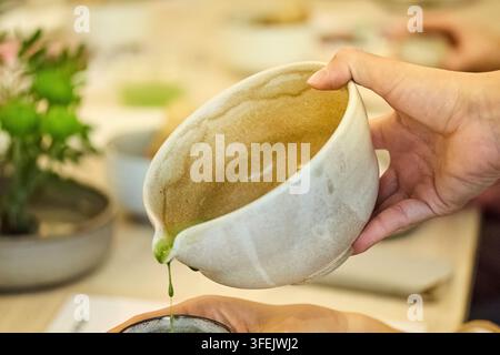 Mano che versa tè matcha durante una cerimonia tradizionale giapponese Foto Stock