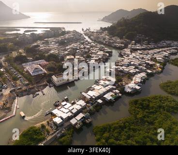 Le barche navigano nei canali di Tai O, un villaggio di pescatori storico con case su palafitte sull'isola di Lantau, a Hong Kong, per visitare il suo patrimonio unico. Foto Stock