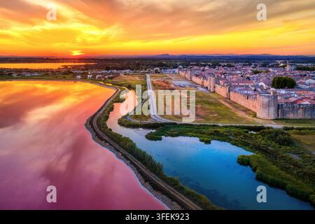Tramonto drammatico sui laghi di sale rosa e sulla città vecchia fortificata medievale di Aigues-Mortes, Camargue, Francia Foto Stock