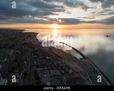 Il tramonto illumina il Herne Bay Pier e la costa del Kent nel sud-est dell'Inghilterra, gettando un bagliore dorato sulla tranquilla città costiera. Foto Stock