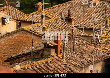 Tetti rustici logorati con camini e antenne in una città europea storica Foto Stock