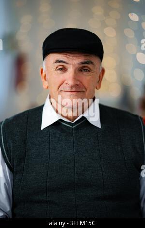 Uomo anziano che sorride indossando un cappello e un gilet di maglia Foto Stock