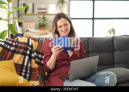 Donna seduta comodamente su un morbido divano tiene un documento importante Foto Stock