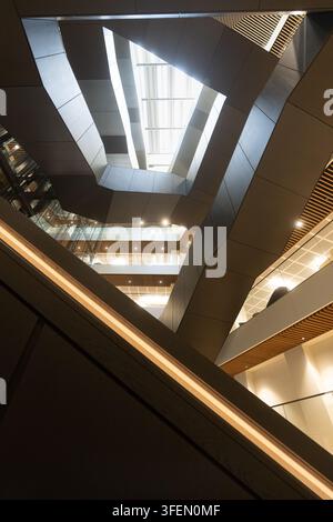 Una vista impressionante dall'angolo basso dell'atrio centrale angolare e dell'architettura moderna all'interno della sede di Dar Group London al 150 Holborn. Foto Stock