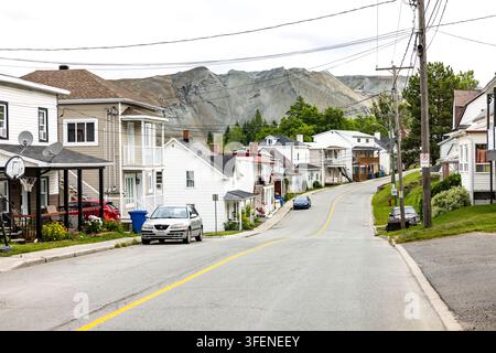 Canada, Thetford Mines, 30-07-2025. Una strada residenziale a Thetford Mines, Quebec, con case e auto parcheggiate in primo piano, dominata dalla ba Foto Stock