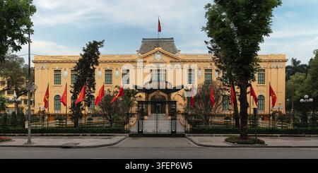 Storica casa degli ospiti coloniale francese del governo a Hanoi, Vietnam, situata accanto a Vuon hoa Dien Hong o Giardino delle Ranocchie. Vista esterna con pareti gialle e bandiere nazionali Foto Stock