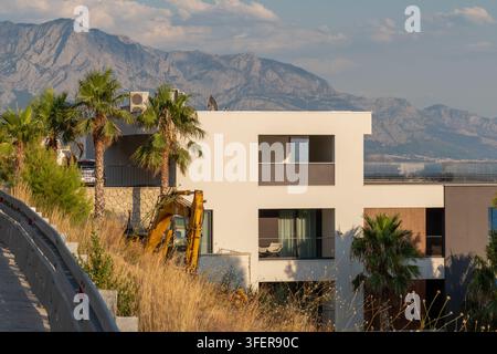 MIMICE, CROAZIA, 4 settembre 2026: Villa costiera moderna si erge tra le palme con le montagne che si stagliano sullo sfondo. Foto Stock