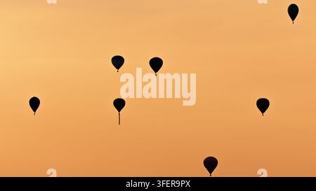 Vista aerea di più mongolfiere che galleggiano nel cielo dorato durante il tramonto in Polonia. Foto Stock