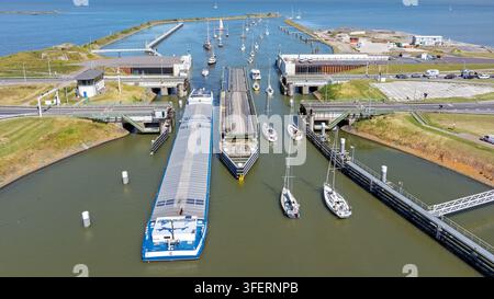 Vista aerea del complesso di chiuse con una grande nave da carico e diverse barche a vela che navigano nel canale a Kornwerderzand, Frisia, Paesi Bassi. Foto Stock