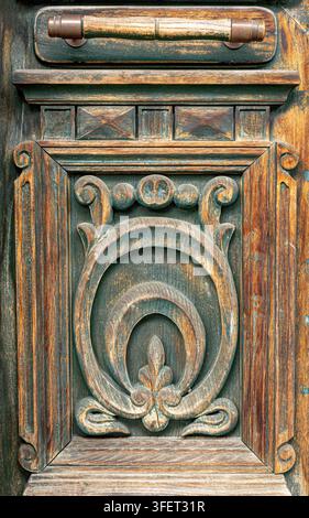 Porta in legno intagliata con texture consumata, maniglia antica e ornamento decorativo Foto Stock