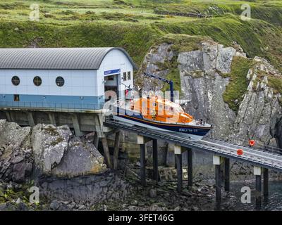 St Davids, Regno Unito – 16 maggio 2026: Veduta aerea della stazione di salvataggio di St Justinian con un canotto di salvataggio RNLI sulla scivolo, circondata da coste frastagliate Foto Stock