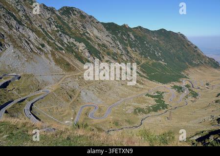 L'autostrada serpeggiante Transfagarasan si snoda attraverso un alto passo di montagna nelle montagne Făgăraș sotto un cielo blu, Carpazi meridionali, Romania. Foto Stock