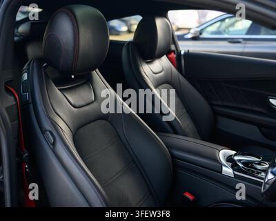 I sedili in pelle nera hanno dettagli di cuciture rosse. I poggiatesta sono inclinati verso il conducente. La console centrale ospita comandi e pulsanti moderni. La sensazione degli interni Foto Stock