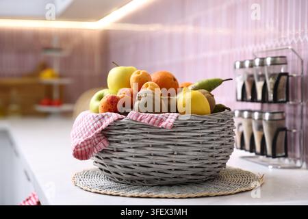 Vari frutti freschi in un cesto di vimini su un piano di lavoro al chiuso Foto Stock