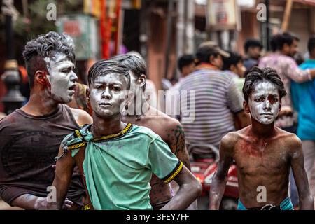 Giovani uomini coperti di polvere Holi durante le celebrazioni di strada a Varanasi, in India. Foto Stock