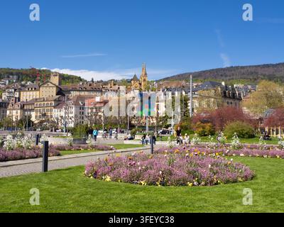 Neuchâtel, Svizzera - 19 aprile 2025: Vista verso il centro storico dalla giardino con fiori in fiore situato sul lago Lemano Foto Stock