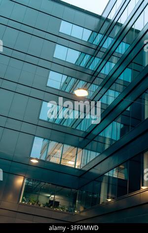 Una fotografia verticale a basso angolo guarda verso l'interno del cortile di un edificio commerciale contemporaneo. Pannelli murali metallici scuri incorniciano file di l Foto Stock