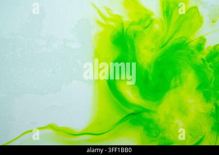 Uno sfondo astratto vibrante con inchiostro o pittura acquerello verde brillante e giallo limone che si diffonde e si muove dolcemente su una tela leggera e texture Foto Stock