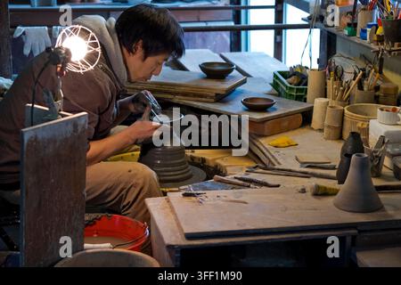 Uomo giapponese che crea un vaso di ceramica su una ruota da vasaio all'interno di una bottega di ceramica nella città di Shigaraki, prefettura di Shiga, Giappone. Foto Stock