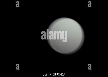 Luce circolare bianca sfocata astratta che brilla dolcemente su uno sfondo nero solido, mostrando un effetto bokeh minimalista e una sfera a fuoco morbido. Astratta w Foto Stock