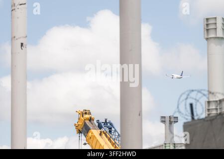 Rinas, Albania - 03 giugno 2026: Vista di un aereo che vola nel cielo sopra l'aeroporto internazionale di Tirana, visto da dietro pilastri di costruzione e una y Foto Stock