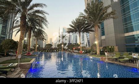 Ambientazione del primo pomeriggio sul Burj Khalifa alto, appartamenti e uffici moderni rialzati attorno al molo della piscina all'aperto illuminato al JW M Foto Stock