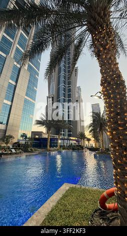 Ambientazione del primo pomeriggio sul Burj Khalifa alto, appartamenti e uffici moderni rialzati attorno al molo della piscina all'aperto illuminato al JW M Foto Stock
