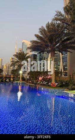 Ambientazione del primo pomeriggio sul Burj Khalifa alto, appartamenti e uffici moderni rialzati attorno al molo della piscina all'aperto illuminato al JW M Foto Stock