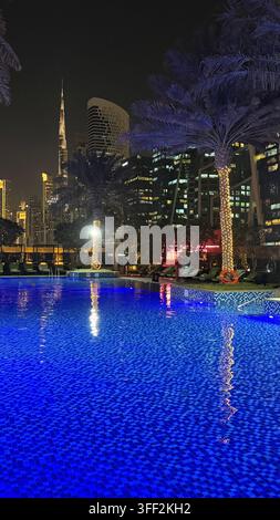 Ambientazione del primo pomeriggio sul Burj Khalifa alto, appartamenti e uffici moderni rialzati attorno al molo della piscina all'aperto illuminato al JW M Foto Stock