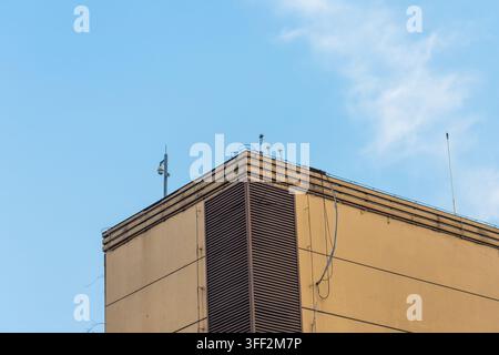 Tetto di un edificio che mostra una telecamera di sicurezza e un'antenna di comunicazione contro un cielo blu terso Foto Stock