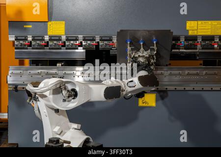 Braccio robotico industriale che aziona una piegatrice automatica per la formatura e la produzione di metalli di precisione Foto Stock