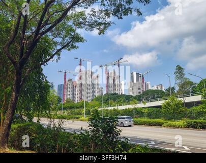 autostrada urbana con diversi blocchi residenziali ad alta altezza in costruzione sullo sfondo, Singapore Foto Stock
