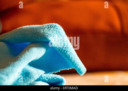 Vista ravvicinata di materiale in pile blu morbido che mostra una trama vellutata e dettagli del tessuto su uno sfondo arancione sfocato. Ideale per la pubblicità del settore tessile. Foto Stock