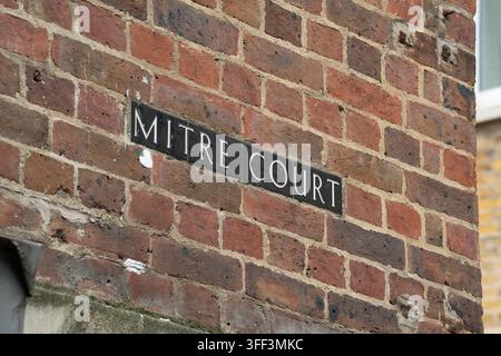 Un cartello su un muro di mattoni rossi identifica Mitre Court, un vicolo storico fuori Fleet Street a Londra, per guidare i pedoni attraverso l'area. Foto Stock