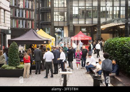 I dipendenti d'ufficio mangiano e socializzano ai food truck di Mex Club durante il pranzo fuori dall'edificio 10 Fleet Place a Londra. Foto Stock