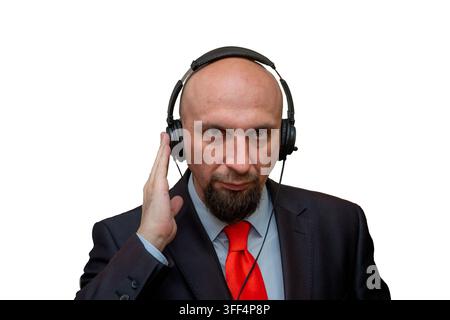Uomo d'affari calvo serio in giacca e cravatta che indossa delle cuffie e tocca un orecchio. Foto Stock
