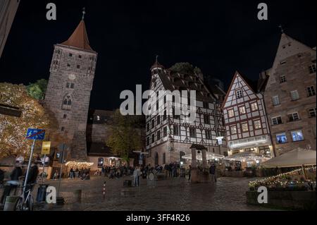 Piazza Tiergärtnertor di notte a Norimberga, Germania, con la torre Tiergärtnertorturm, la casa Pilatus, ristoranti e persone sulla piazza. Foto Stock