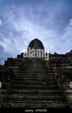 Un piano basso delle ripide scale di pietra che conducono al tempio di Angkor Wat, in Cambogia, sotto un cielo nuvoloso. Foto Stock
