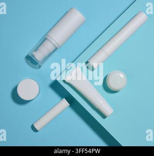 Un set di packaging cosmetici bianchi, creme, tubetti e bottiglie su uno sfondo blu. Vista dall'alto. Foto Stock