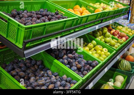 Esposizione di frutta fresca nella sezione ortofrutticola del supermercato con prugne, mele, arance e meloni, vendita al dettaglio di generi alimentari, alimentazione sana, acquisti di cibo, abbondanza del mercato. Foto Stock