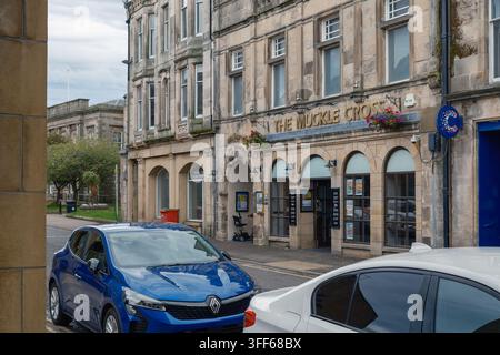 Classico edificio in pietra del The Muckle Cross Pub si trova a Elgin in Scozia mentre le auto sono parcheggiate lungo la strada durante un'ora di luce diurna a Moray Foto Stock