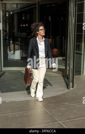 Donna d'affari professionista che esce dall'edificio per uffici con una valigetta Foto Stock