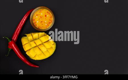 Vista dall'alto di marmellata di mango al peperoncino, mango a cubetti e due peperoncini su sfondo grigio. Banner di salsa di mango al peperoncino. Foto Stock