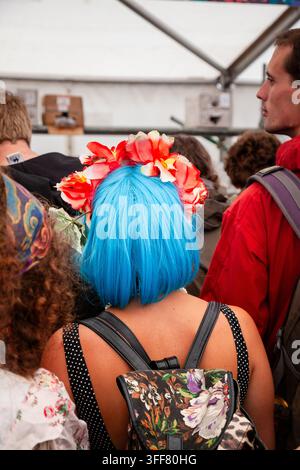 SCENA DI FOLLA AL FESTIVAL CON DONNA DAGLI CAPELLI BLU, REPORTAGE, GREEN MAN FESTIVAL 2013, BRECON, GALLES, REGNO UNITO, 2013: Di spalle, una donna con capelli blu brillanti e una corona di fiori rossi si trova in una folla al festival, indossando uno zaino floreale e una maglia a pois. Foto: Rob Watkins. INFO: Il Green Man Festival si tiene ogni anno a agosto nei Brecon Beacons. Celebra musica alternativa, arti, letteratura, scienza e una cultura adatta alle famiglie in uno splendido scenario montano. L’evento del 2013 è stata l’edizione del 10° anniversario. Foto Stock