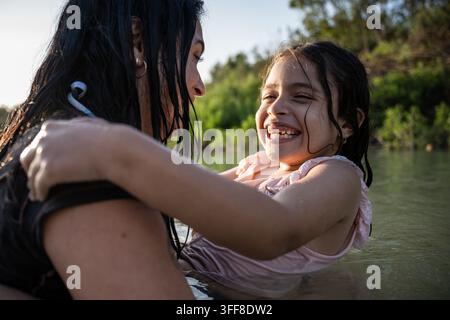 Figlia felice che ride tra le braccia di sua madre Foto Stock