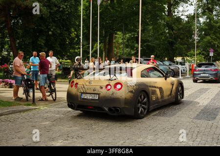 Sopot, Polonia - 25 luglio 2026: Vista posteriore di un'auto da corsa modificata con motivo mimetico e aletta posteriore che attraversa un ambiente urbano con persone che osservano nelle vicinanze Foto Stock
