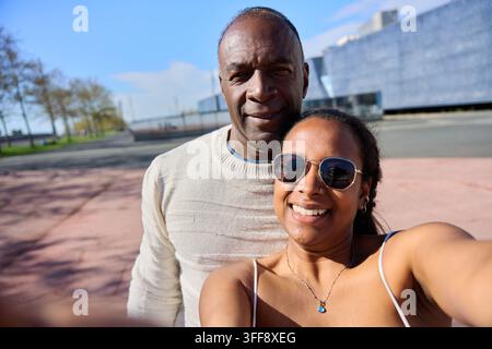 Padre che sorride all'aperto con sua figlia che scatta un selfie insieme. Foto Stock