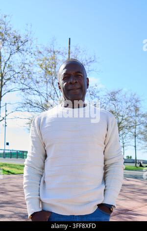 Uomo maturo che sorride all'aperto in un parco urbano. Foto Stock